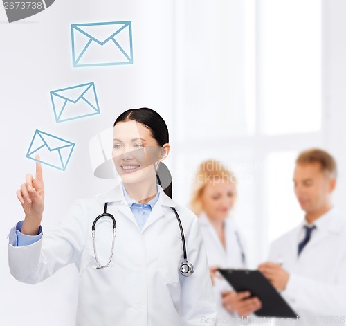 Image of smiling female doctor pointing to envelope