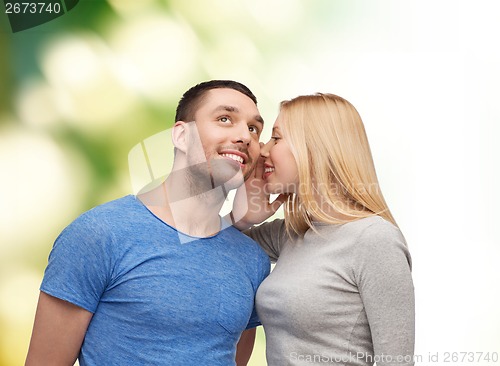 Image of smiling girlfriend telling boyfriend secret