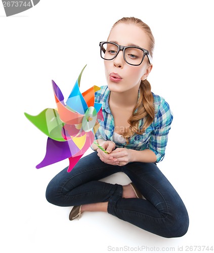 Image of woman in eyeglasses sitting on floor with windmill