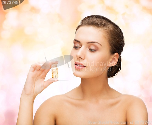 Image of beautiful woman showing bottle with golden dust