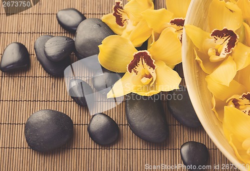 Image of massage stones with orchid flowers on mat