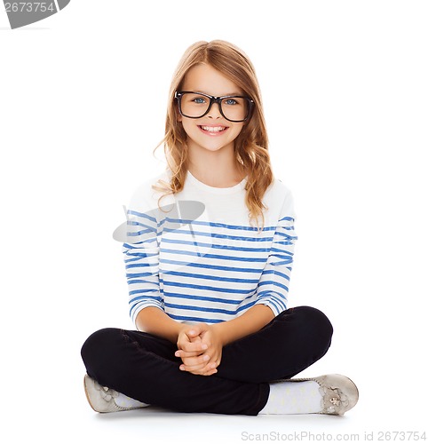 Image of smiling girl in eyeglasses sitting on floor