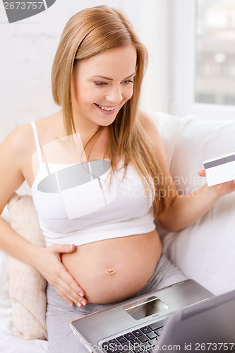 Image of smiling pregnant woman with laptop computer