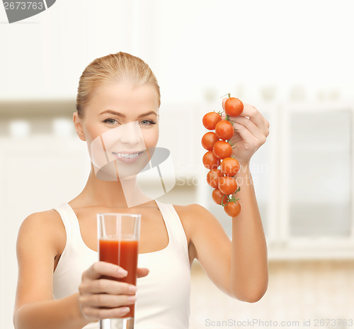 Image of smiling woman holding glass of juice and tomatoes