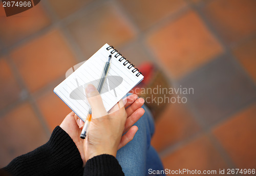 Image of Woman hand with notepad and pen