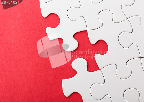 Image of Incompleted white puzzle with red background