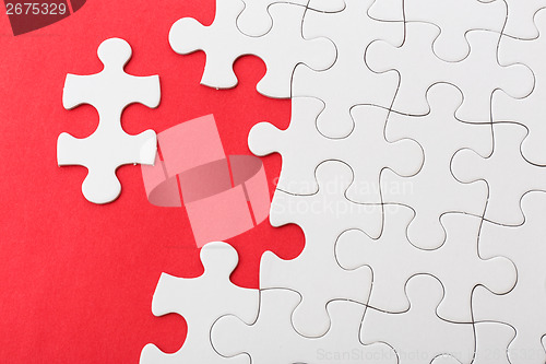 Image of Incompleted white puzzle on red background