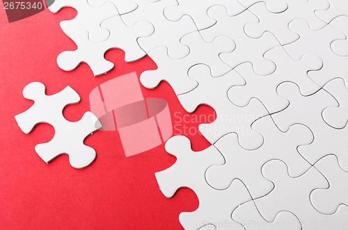 Image of Incomplete puzzle with missing piece over red background