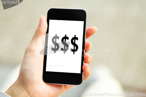 Image of Human hand holding mobile phone with dollar sign on screen