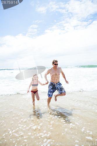 Image of Happy father and daughter running from waves at beach