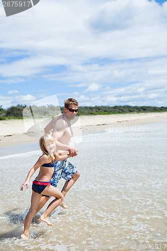 Image of Happy father and daughter running along beach in shallow water