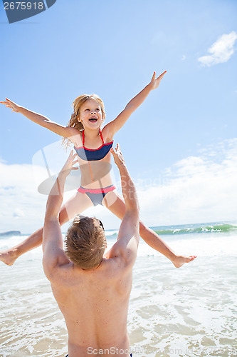 Image of Father throwing young daughter in air at beach