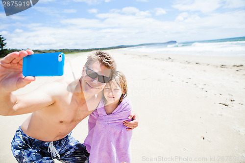 Image of Father taking selfie photograph with daughter at beach