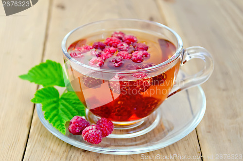 Image of Tea with raspberry and leaf in a cup on board