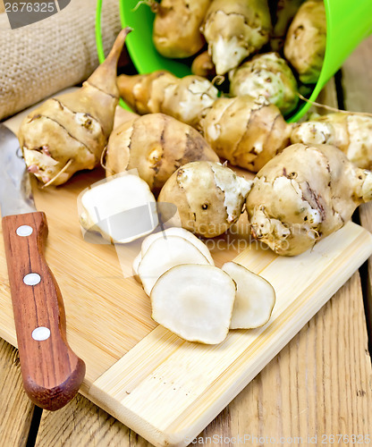 Image of Jerusalem artichokes cut with knife and bucket on board