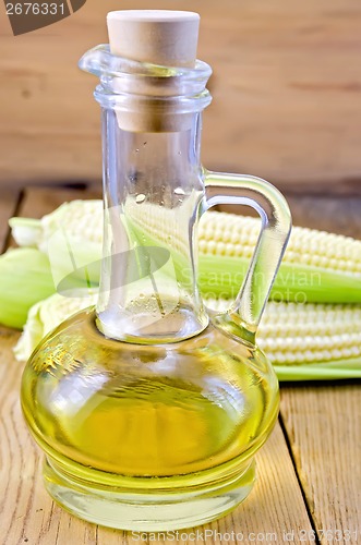 Image of Corn oil in a carafe with corncobs on board