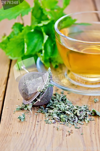 Image of Herbal tea from melissa in cup with strainer on board