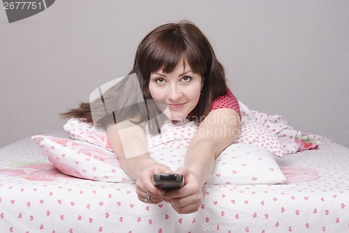 Image of Cheerful girl in bed watching TV