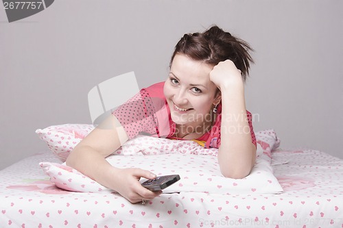 Image of girl on bed laughing while watching TV