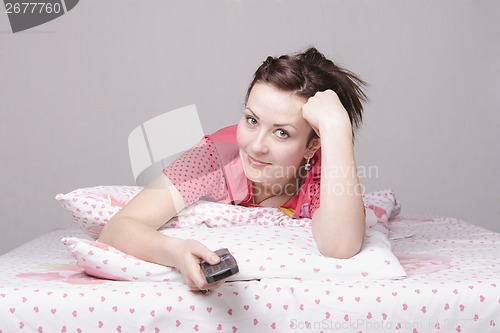 Image of girl lying in bed and watching TV