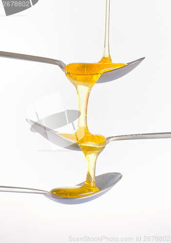 Image of Honey dripping over three silver teaspoonful 
