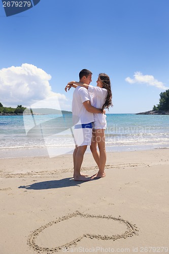 Image of happy couple have fun on the beach with heart on sand