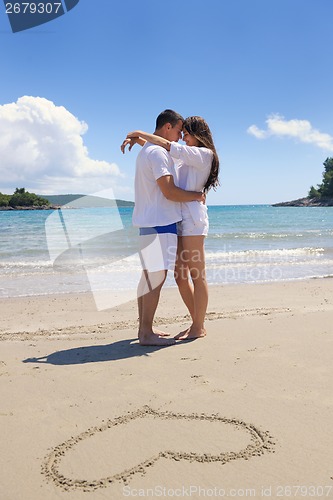 Image of happy couple have fun on the beach with heart on sand