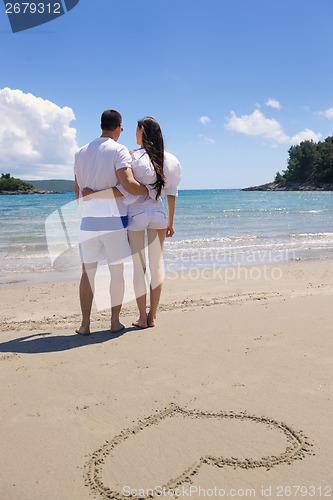 Image of happy couple have fun on the beach with heart on sand