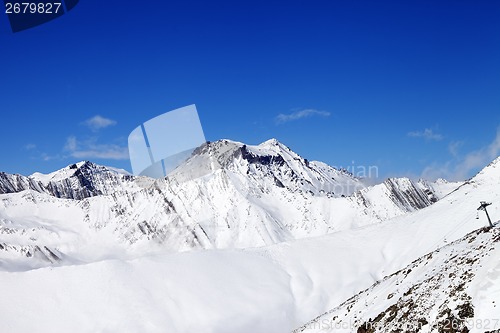 Image of Off-piste slope and snowy mounts against blue sky