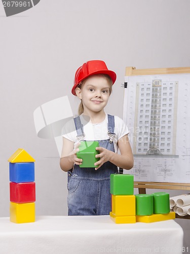 Image of The girl in helmet builds a house on drawing