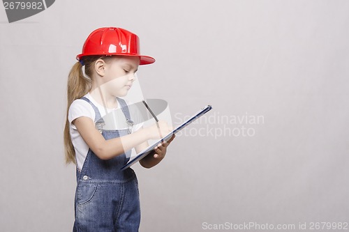 Image of child stands helmet and writes in the folder