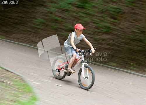 Image of Boy racing on bike through park