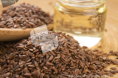 Image of Linseed oil and flax seeds on wooden background 