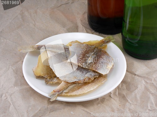 Image of fish on white plate and beer bottle