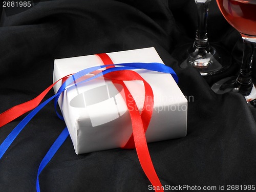 Image of wine glass cup and white present on black background