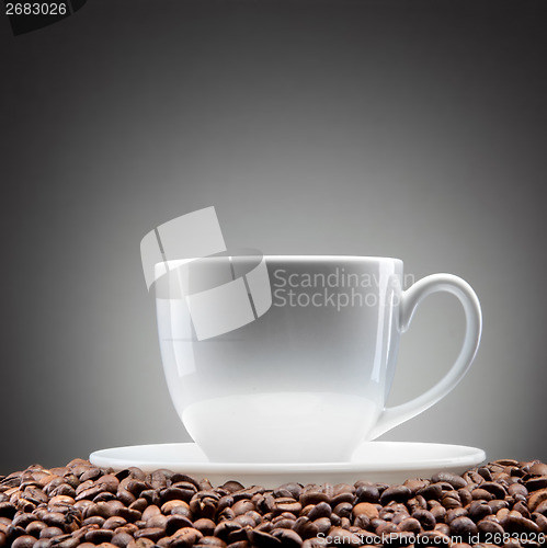 Image of white cup with coffee beans on black