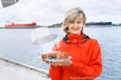 Image of Happy woman holding cooked crab on plate