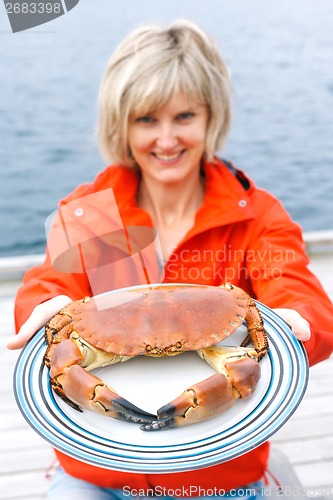 Image of Happy woman giving cooked crab on plate