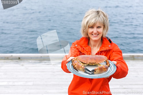 Image of Happy woman giving cooked crab on plate