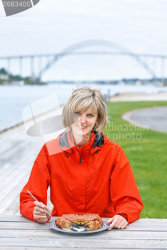 Image of Happy woman eating crab