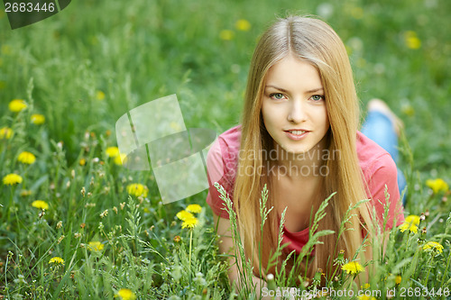 Image of Spring girl lying on the field of dandelions