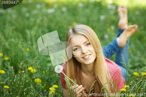 Image of Spring girl lying on the field of dandelions