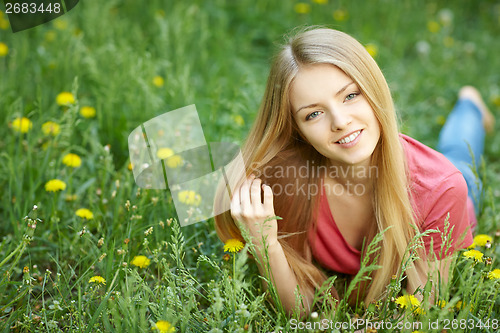 Image of Spring girl lying on the field of dandelions