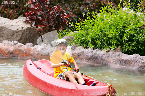 Image of Happy boy paddling kayak on the river and enjoying a lovely summ