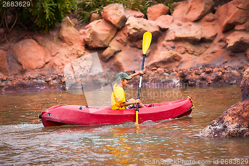 Image of Happy boy paddling kayak on the river and enjoying a lovely summ