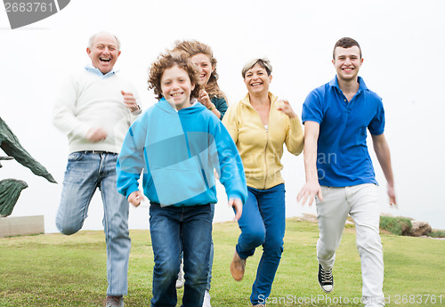 Image of Smiling family running in the grass