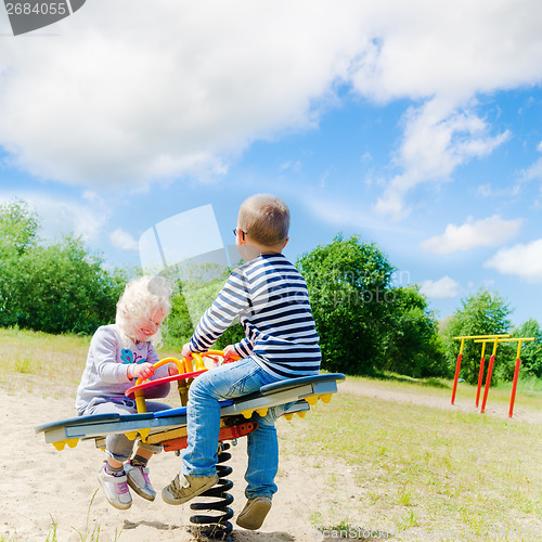 Image of Boy and girl swinging on a swing