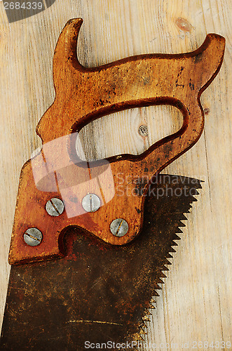 Image of old rusty saw on wooden background with Grunge Filter