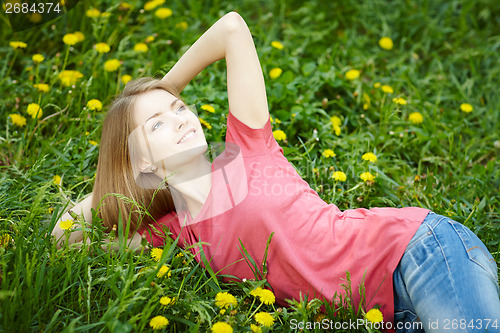 Image of Spring girl lying on the field of dandelions