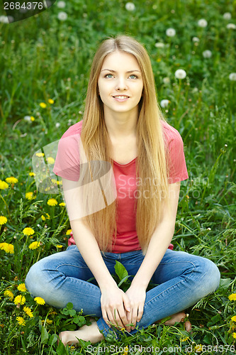 Image of Female sitting on the field of dandelions